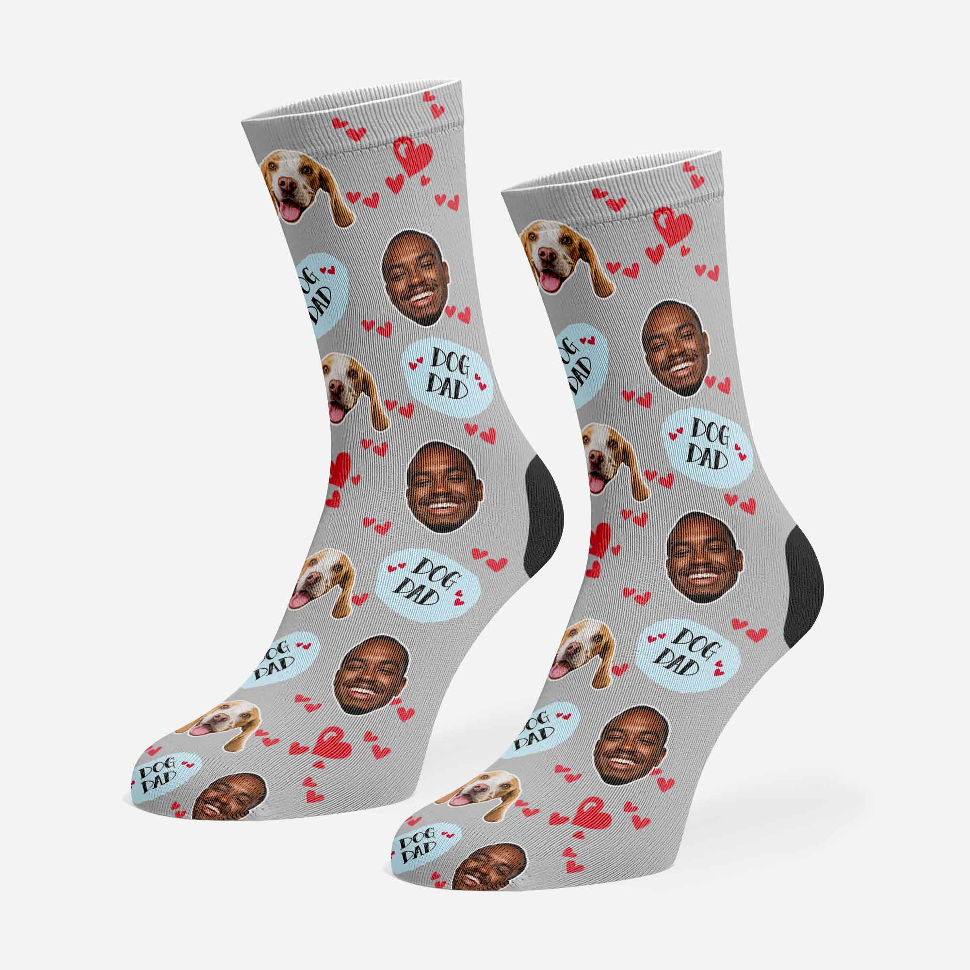 Two socks with a pattern of a man's face, dog faces, and 'Paw Dad' text on a gray background.